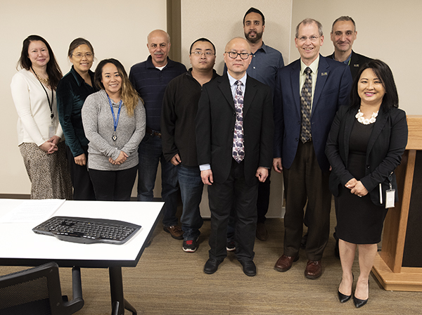 Picture of employees lined up in a row and looking at the camera. David Maeda is in the middle.